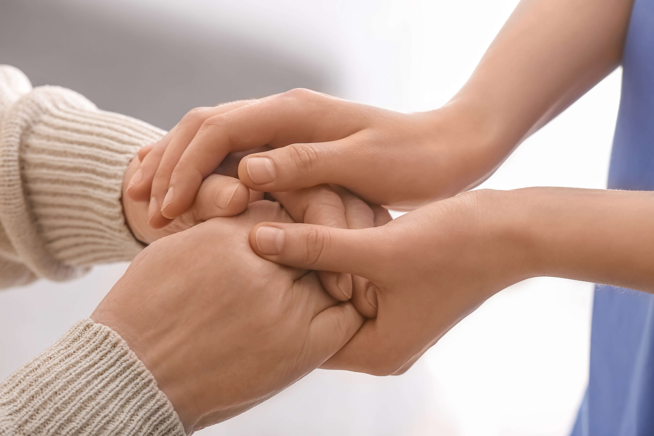 Hænder som holder om andre hænder for at vise omsorg og støtte